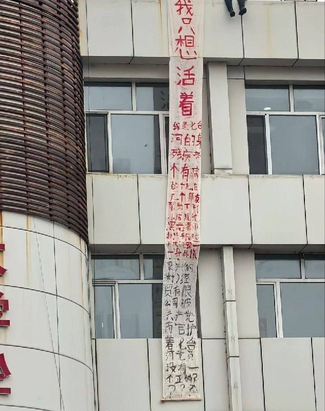 黑龙江省七台河市，一名男子坐在楼边拉横幅维权