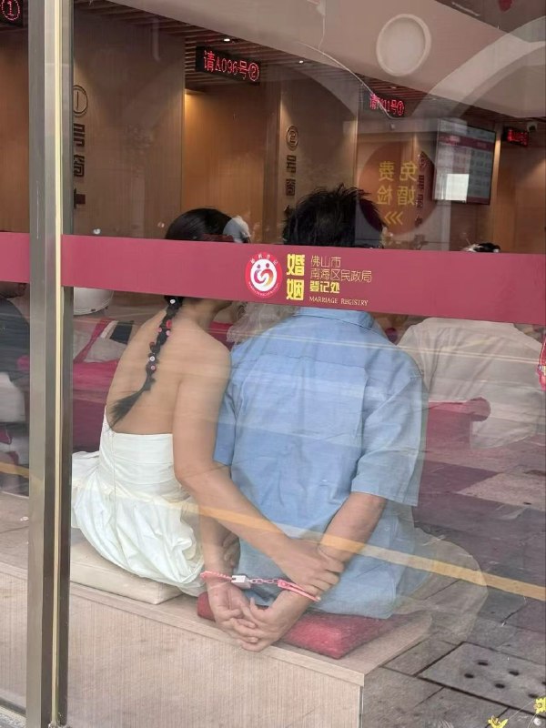 一对在民政局领证的新人，男人的粉色手铐非常形象